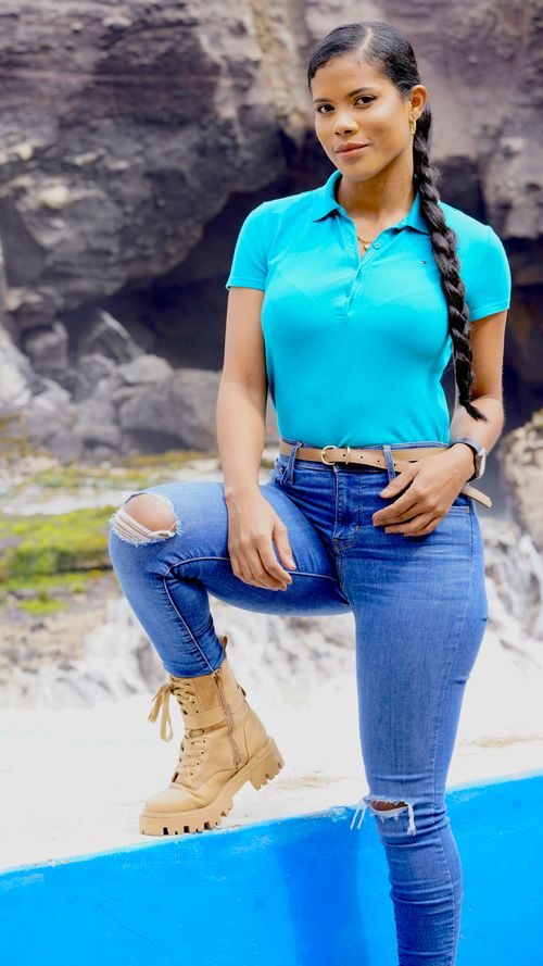 Free Woman standing confidently outdoors in a polo shirt and denim jeans, showcasing a casual and trendy style. Stock Photo