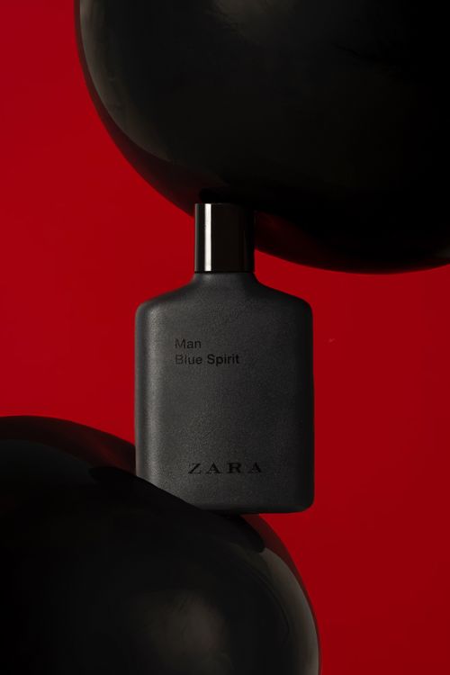 Free Sophisticated black perfume bottle with modern design on a striking red backdrop. Stock Photo