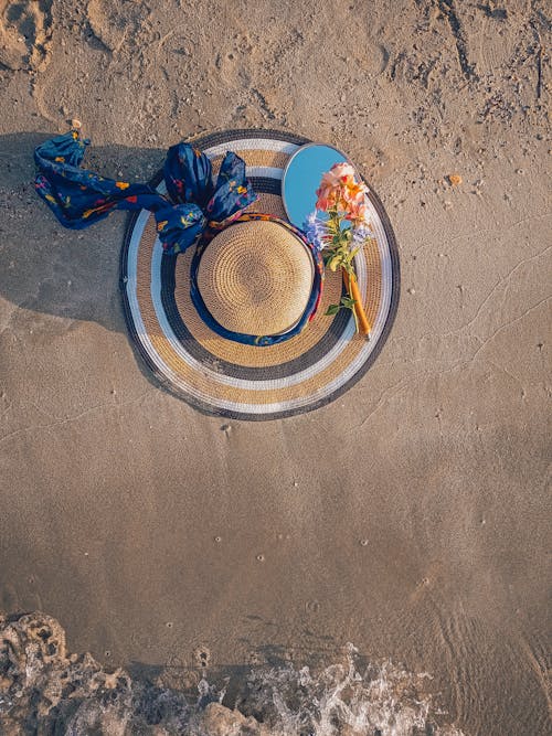 Sun Hat and a Hand Mirror on Beach Sand