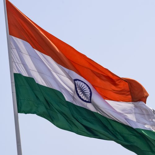 Free A majestic Indian flag gracefully waving against a clear blue sky, symbolizing national pride. Stock Photo