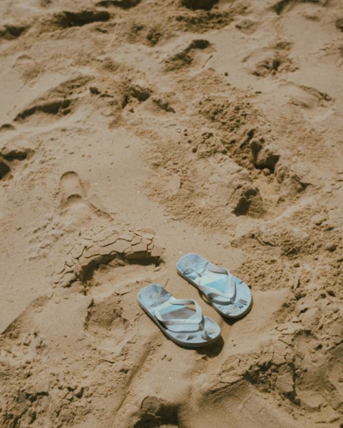 Free Pair of flip flops on a sandy beach, evoking summer vibes and relaxation. Stock Photo