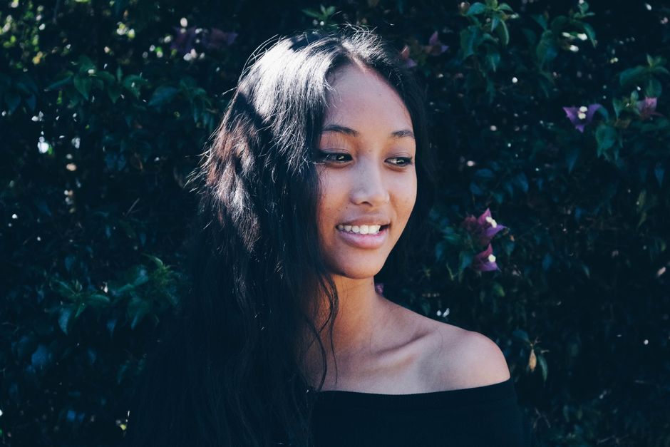 A beautiful woman with long hair smiles naturally outdoors in Madagascar.