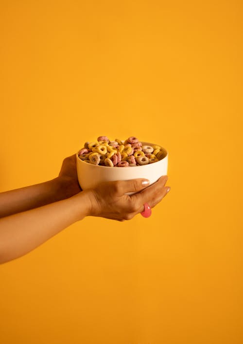 Woman Holding a Bowl of Cereal on Yellow Background 