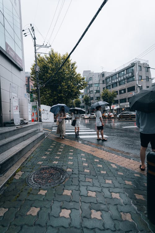 People Standing on the Side of the Road Near a Building During Gloomy Weather