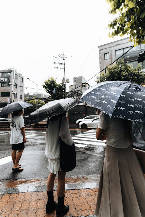 People Under an Open Umbrella Standing on the Side of the Road