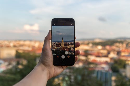 Free Person Taking Picture of Beige Building Using Black Smartphone Stock Photo