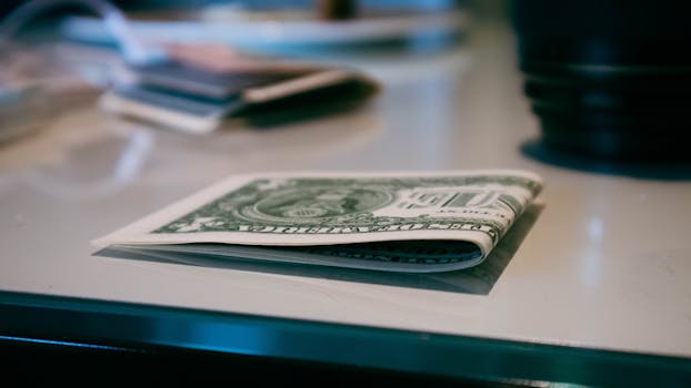 Detailed shot of a folded US dollar note on a reflective surface indoors.