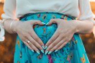 Woman Making a Heart with Her Hands on Her Pregnant Belly 
