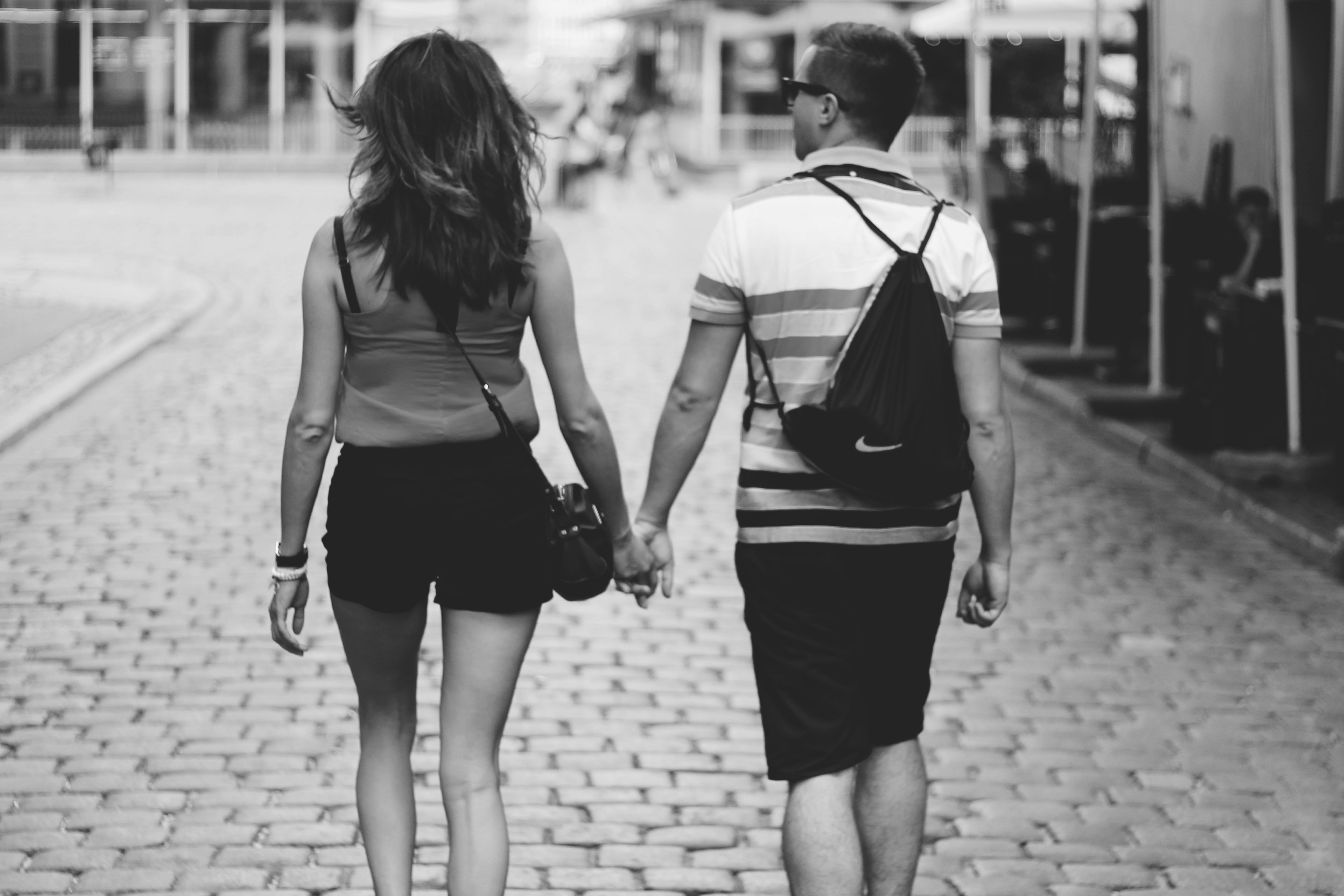 Grayscale Photography Of Man And Woman Holding Hands While Walking