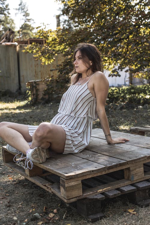 Woman Wearing a Stripe Dress Sitting on a Wooden Crate