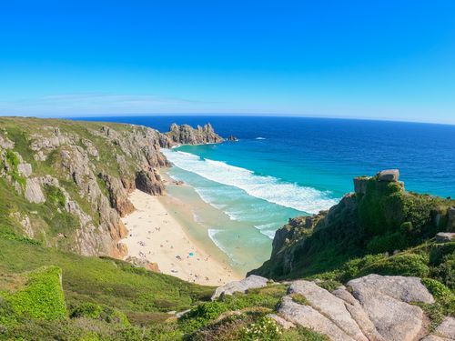 Free Explore a breathtaking cliffside beach with vibrant blue waters under a clear summer sky. Stock Photo