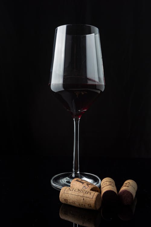 A Glass of Red Wine Near Corks