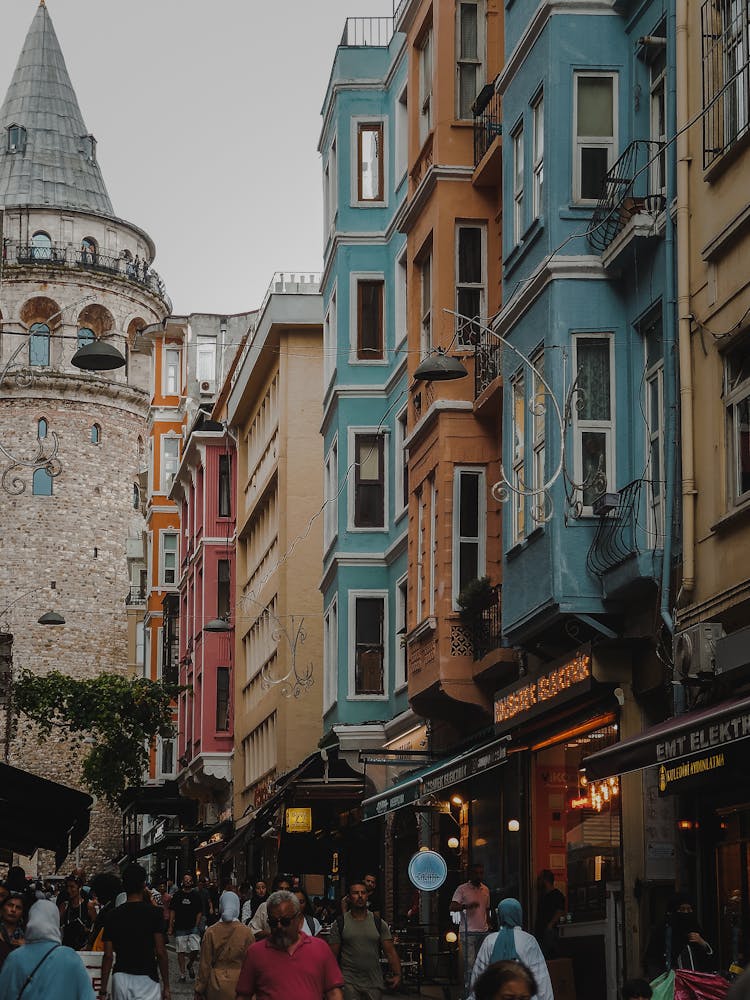 Stores Along A Crowded Street With A Tower In The Background