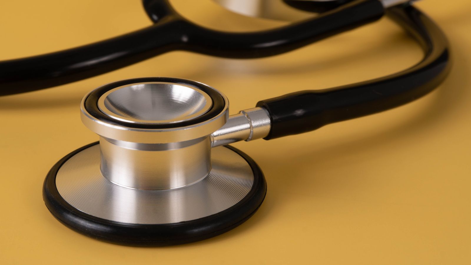 Detailed image of a stethoscope on a vibrant yellow surface.