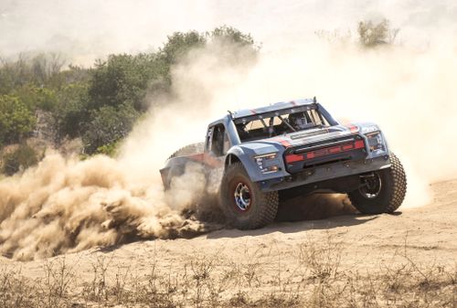 Free High-speed off-road race truck kicking up dust in the Mexican desert, capturing the thrill of motorsport. Stock Photo