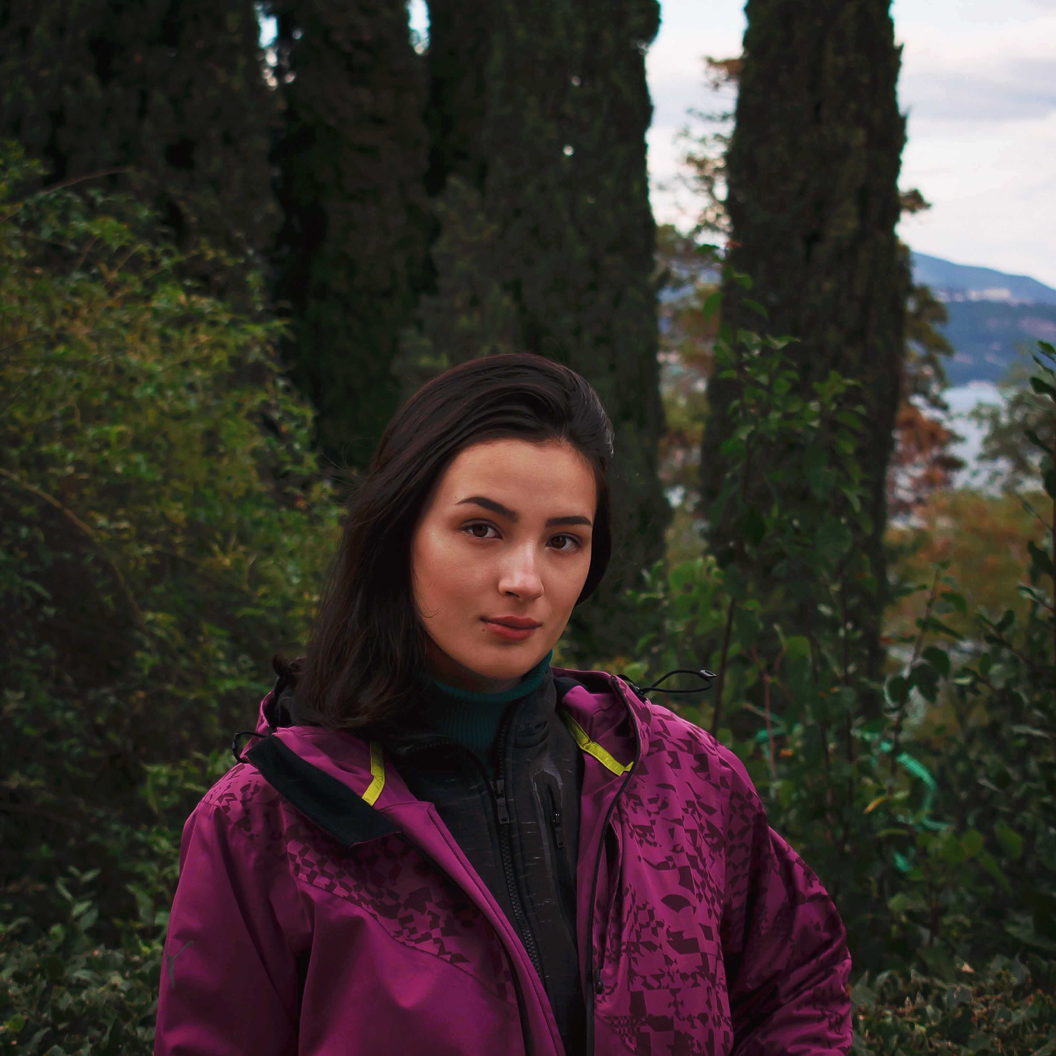 Elegant portrait of a woman in a vibrant purple jacket, set in Livadia's lush garden.
