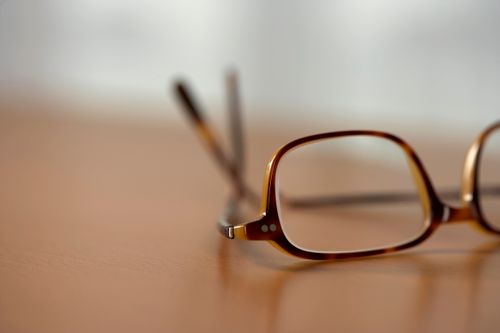 Free A close-up view of stylish brown eyeglasses resting on a wooden table. Stock Photo