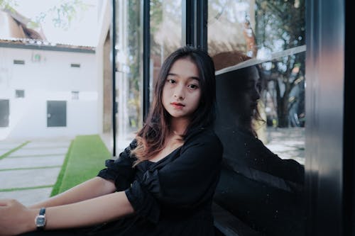 Free Woman in Black Blouse Sitting Beside a Glass Door Stock Photo