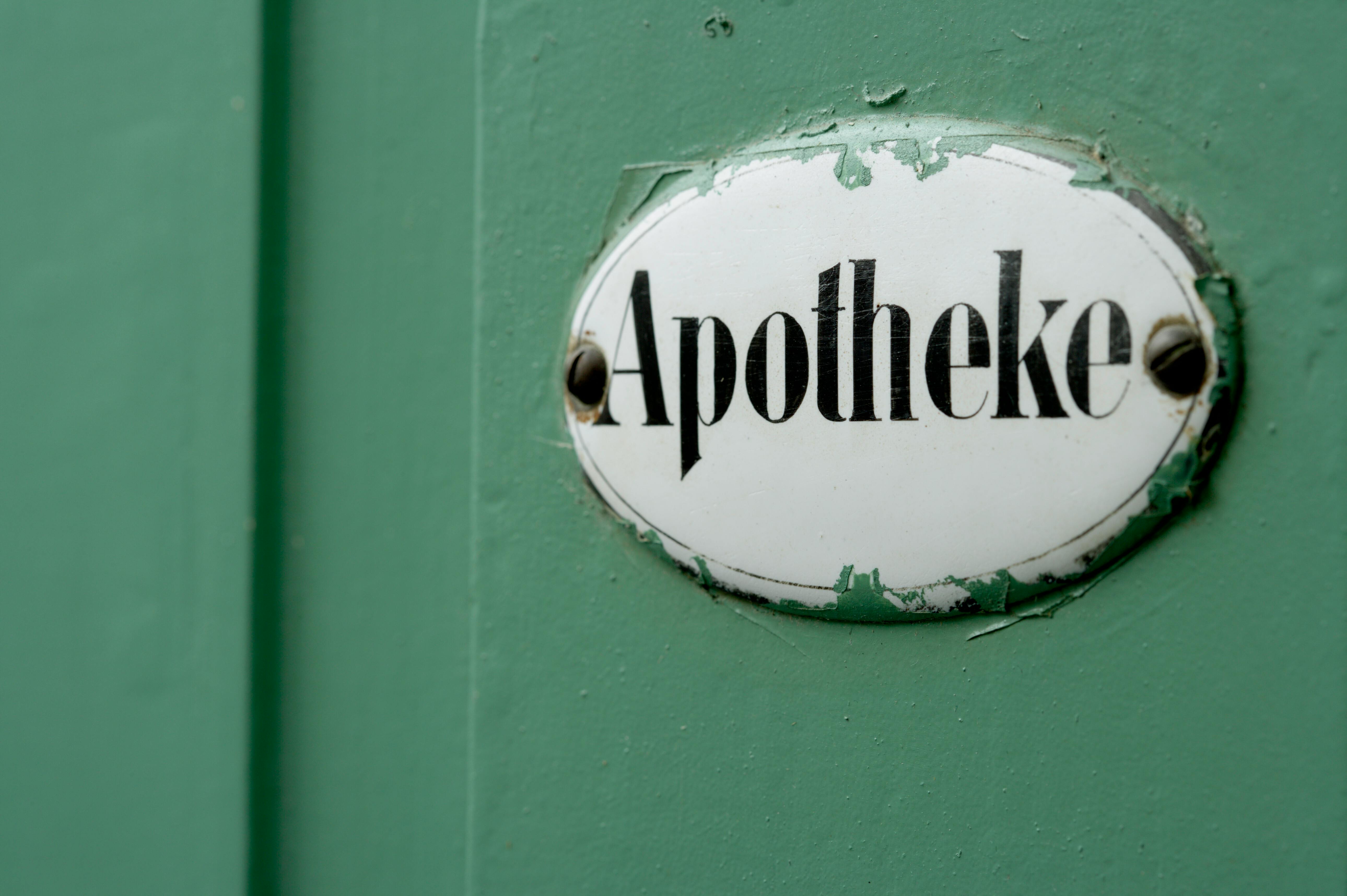 A close-up view of an apotheke sign on a green door symbolizing pharmacy services.