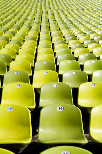 A pattern of empty green stadium seats in neat rows creating a vibrant visual symmetry.