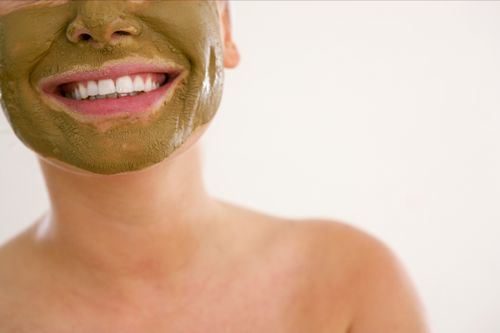 Free Close-up of a smiling woman applying a green cosmetic mask for skincare. Stock Photo