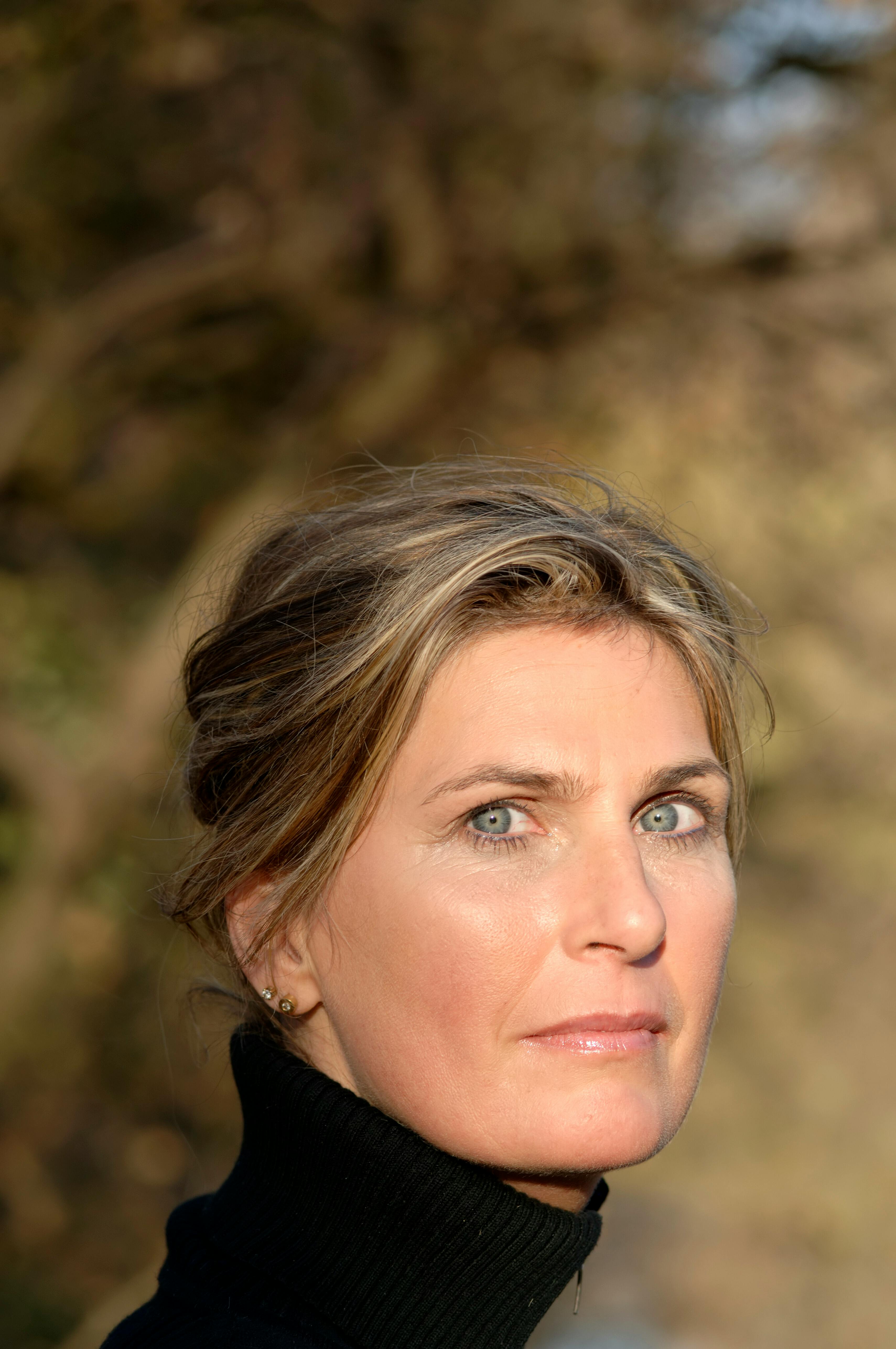 Close-up portrait of a mature woman in natural sunlight, looking directly at the camera.
