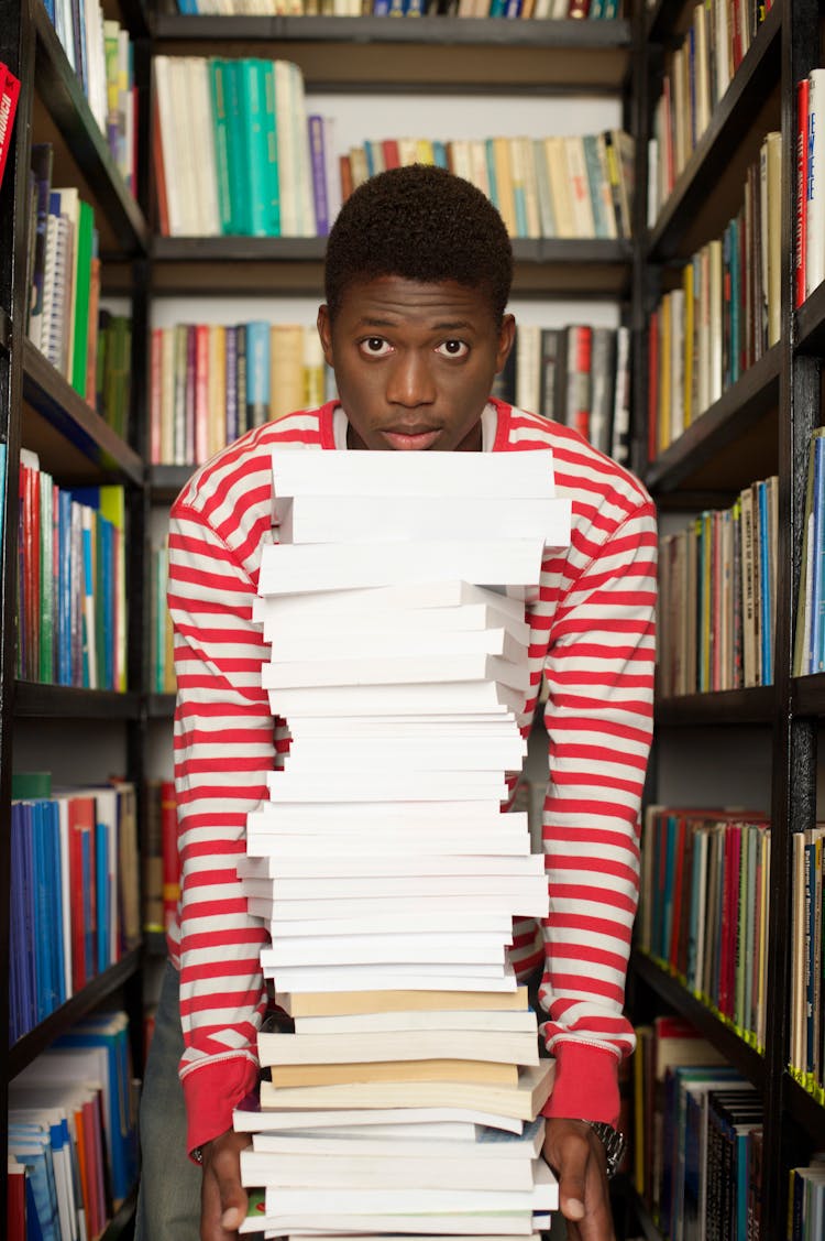 Photo Of A Man Carrying A Stack Of Books