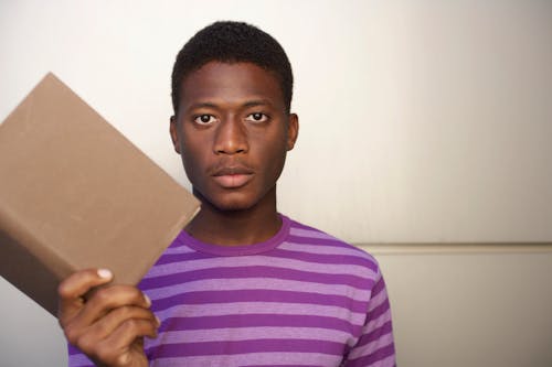 Photo of a Man Holding a Brown Book