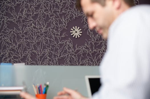 Blurred businessman at a desk with artistic purple wallpaper in the office background.