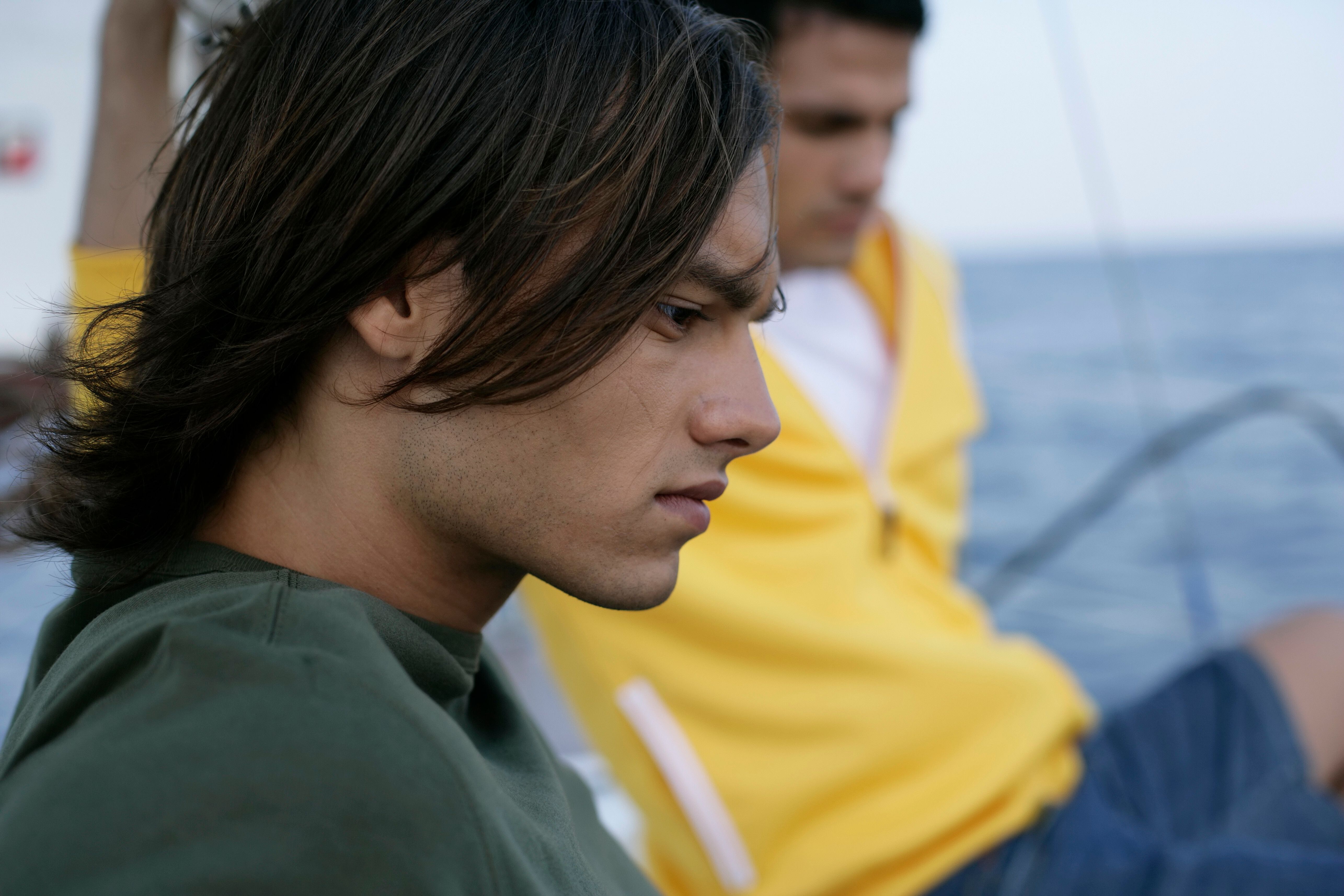 Close-up of a young man in deep thought while sailing. Captures a serene and reflective moment.