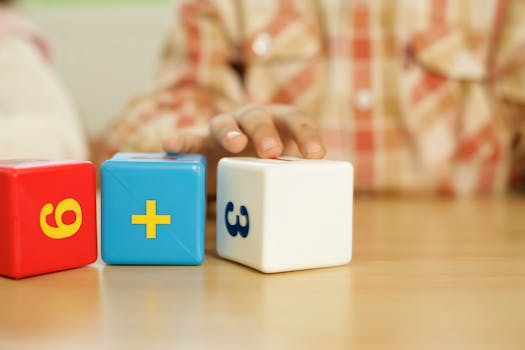Close-up of child's hand touching educational math blocks on desk.
