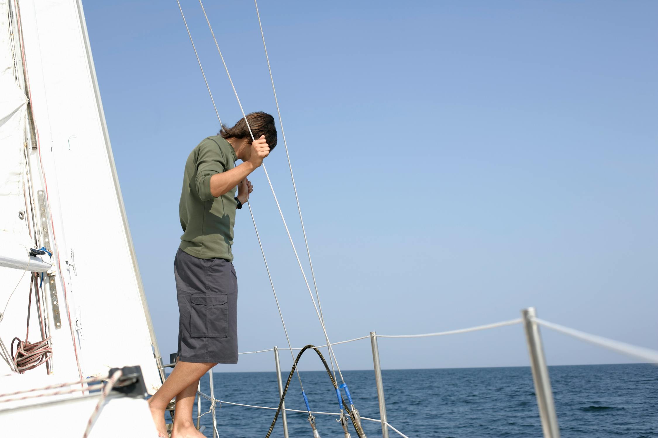 A man in green shirt and black shorts standing on a white boat