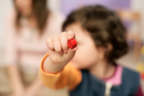 A Kid Holding a Red Wood Toy