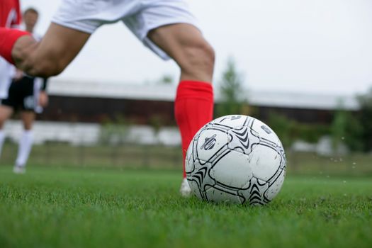 Close-up of a soccer player kicking a ball during a daytime match.