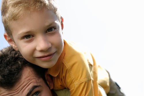 A Boy Piggy Back Riding on His Father's Back