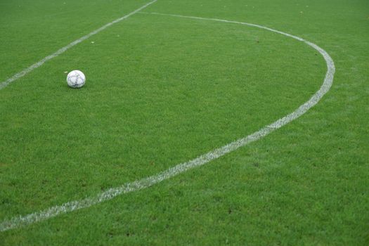 Soccer ball resting on a vibrant green field with white boundary lines.