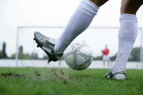 Legs of a Soccer Player Kicking the Ball