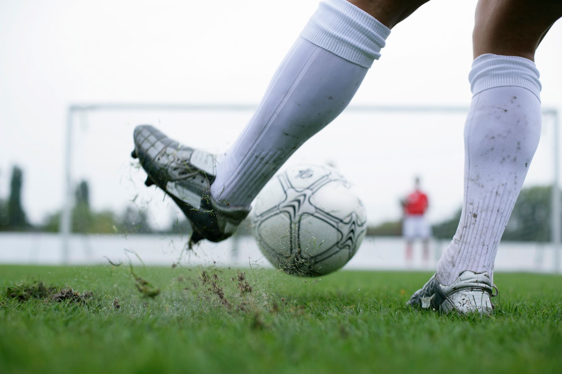 Close-up of a soccer player kicking a ball with motion and intensity on a grass field, showcasing action and sport.