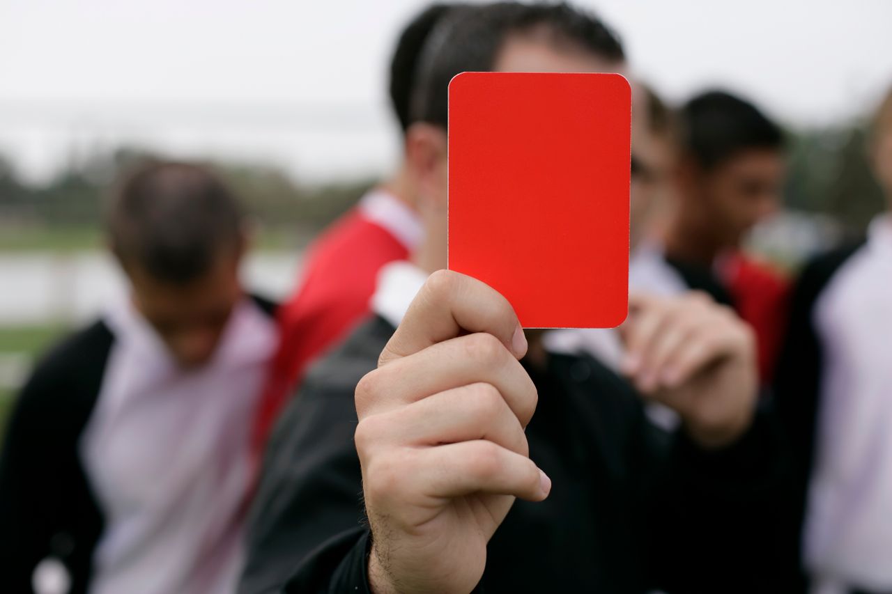 referee showing a red card to players during an outdoor soccer game