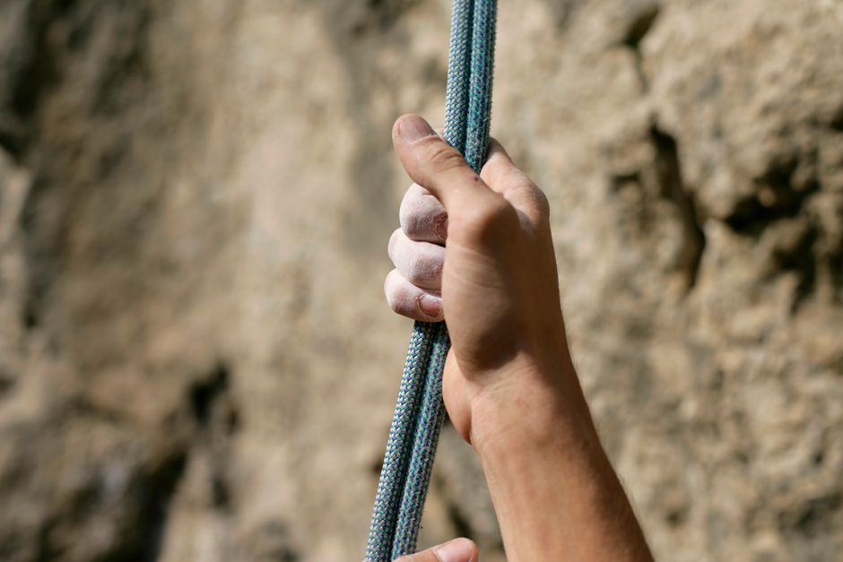 A climber A climber's hand firmly grips a rope against a rocky background.