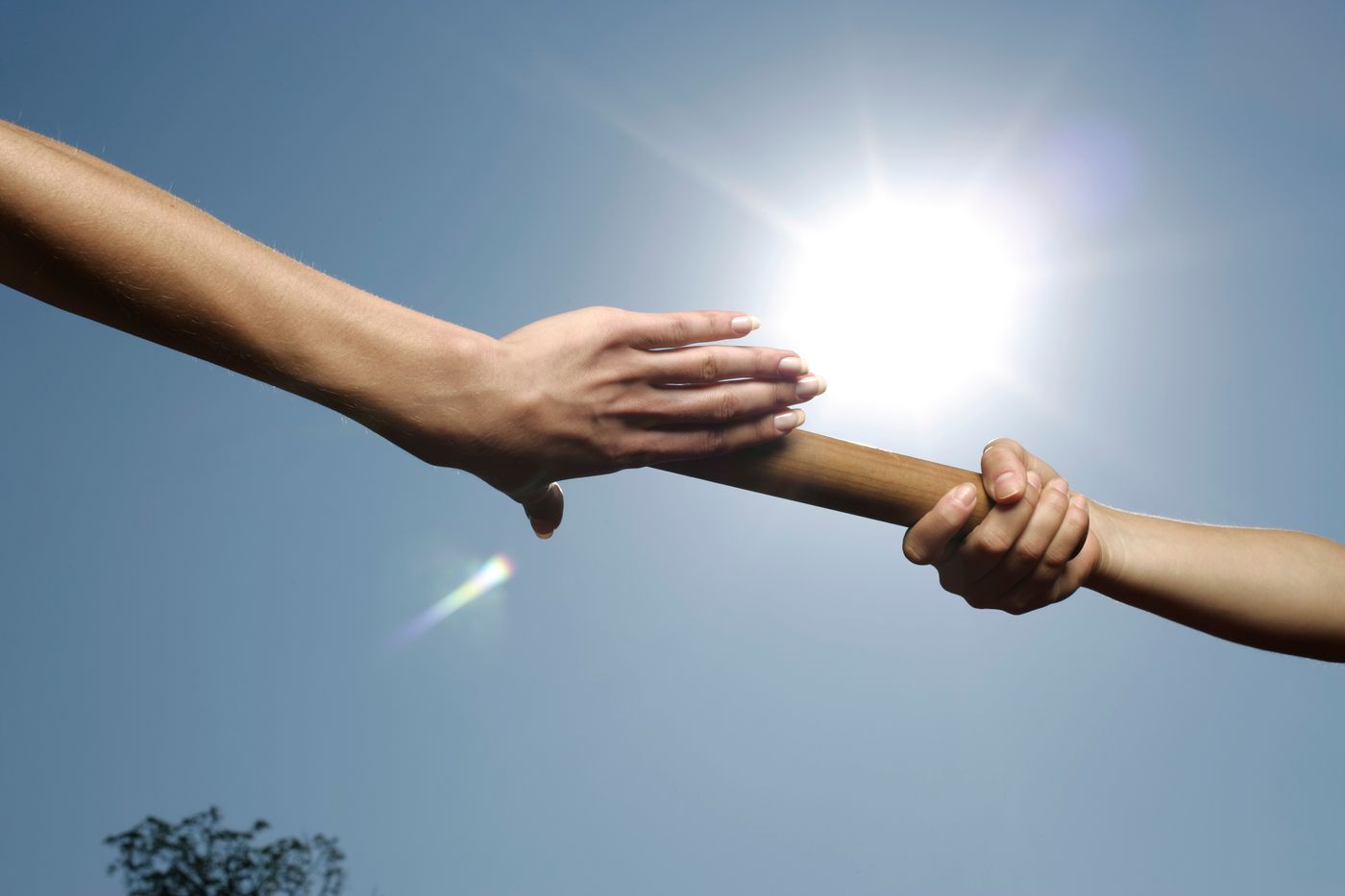 Two hands passing a relay baton under bright sun — BOOM Photography on Pexels