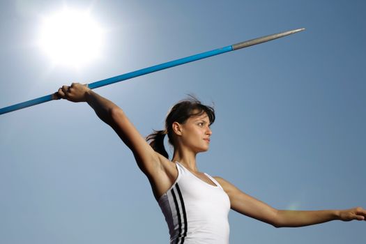 Dynamic shot of a female javelin thrower in action against a bright sky. — photo by BOOM 💥 Photography