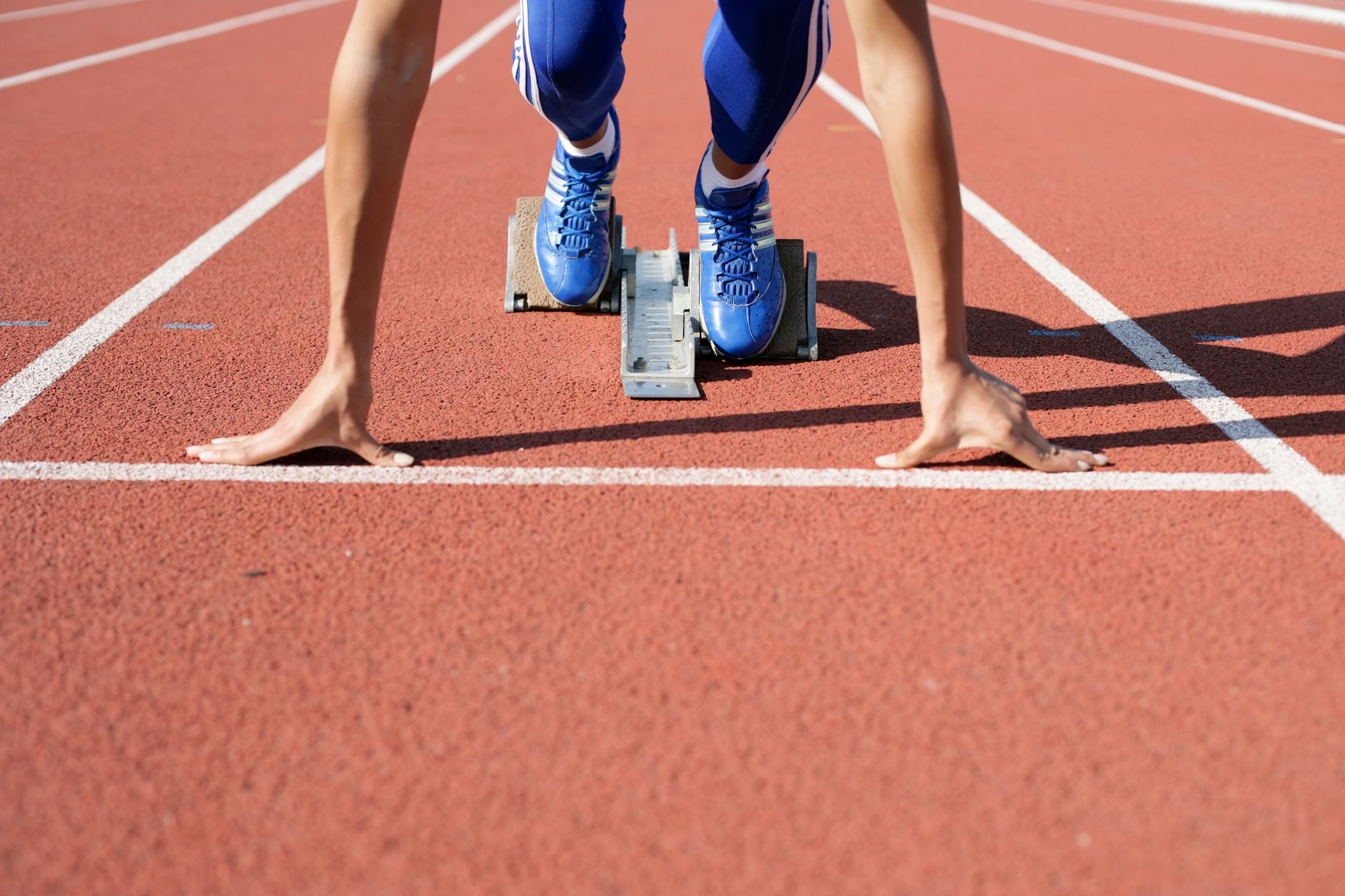 Close-up of an athlete starting a race at the track field on a sunny day.