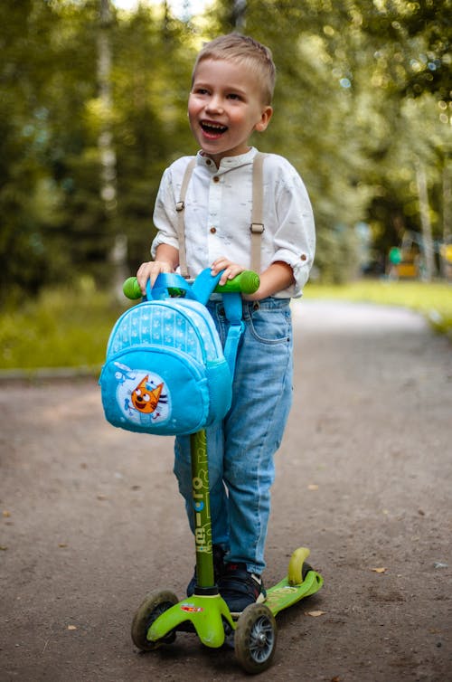 Free Happy Kid Riding a Scooter Stock Photo