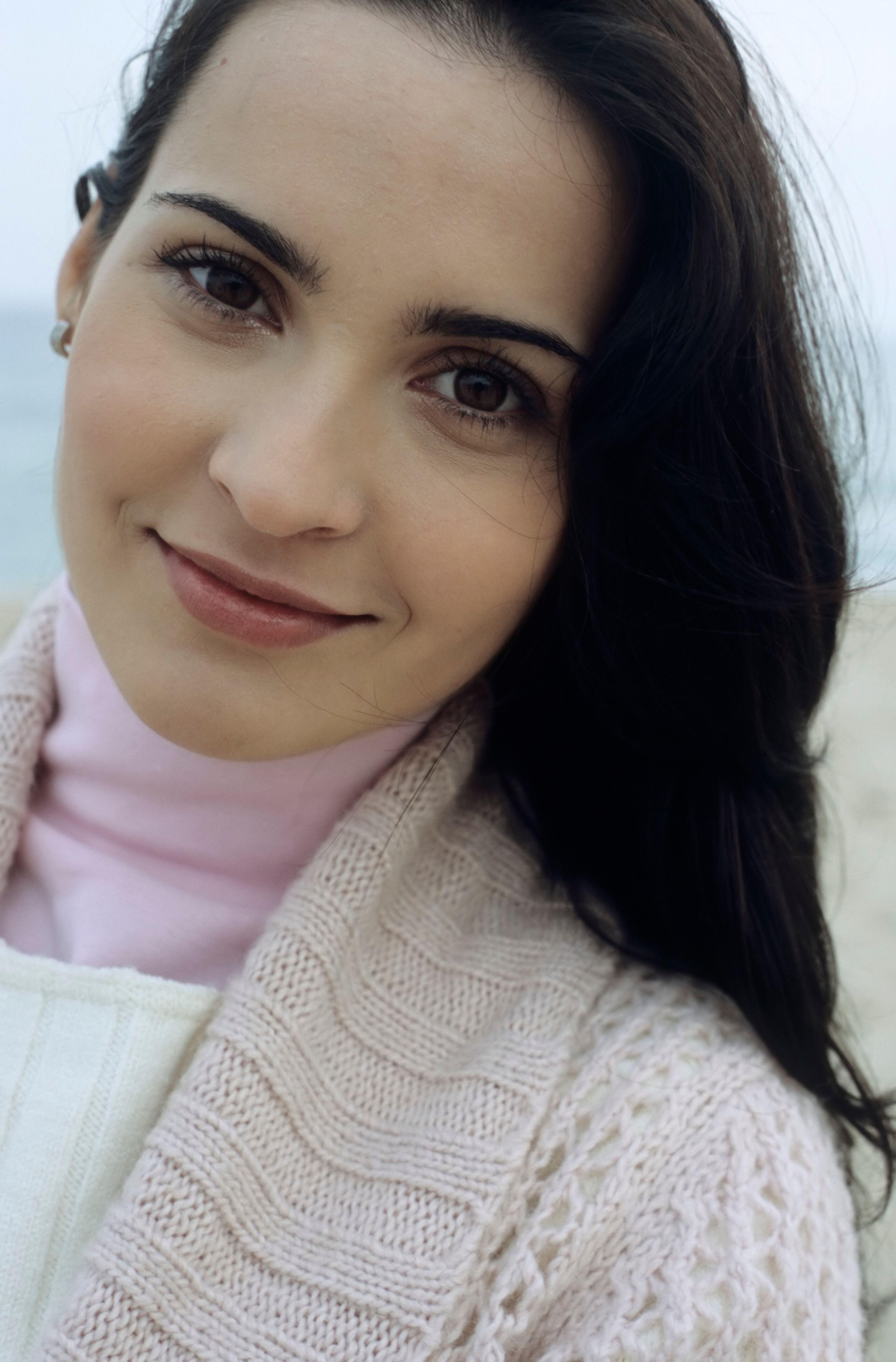 Portrait of a smiling young woman at the beach during winter, showcasing natural beauty.
