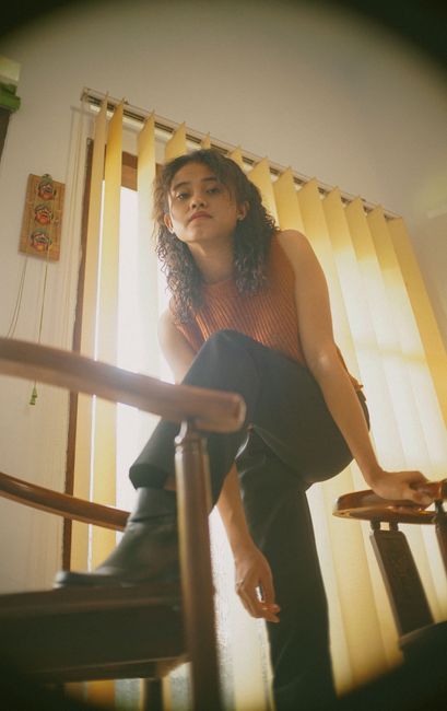 Portrait of a fashionable young woman posing indoors with natural light, in a modern setting.