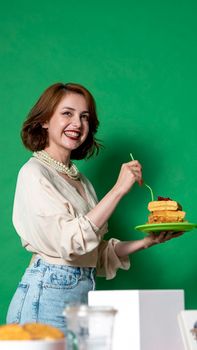 Young woman in casual attire holding a plate of delicious waffles against a green background.
