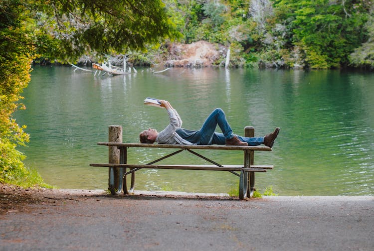 Man Lying On Table While Reading A Book