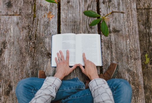 Man Reading Book on Wooden Pier