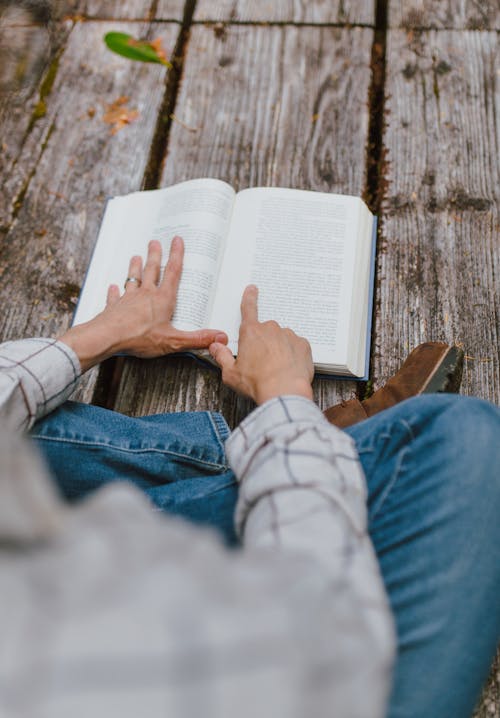 Free Person in Blue Denim Jeans Reading a Book Stock Photo